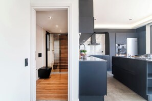 Et moderne køkken med en central ø, indbygget ovn og et stort vindue.