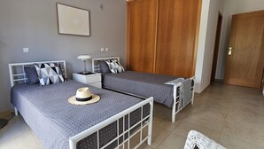Ein Schlafzimmer mit zwei Betten, einer Stehlampe, einem Kleiderschrank und einer Tür.