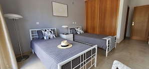 Ein Schlafzimmer mit zwei Betten, einer Stehlampe, einem Kleiderschrank und einer Tür.