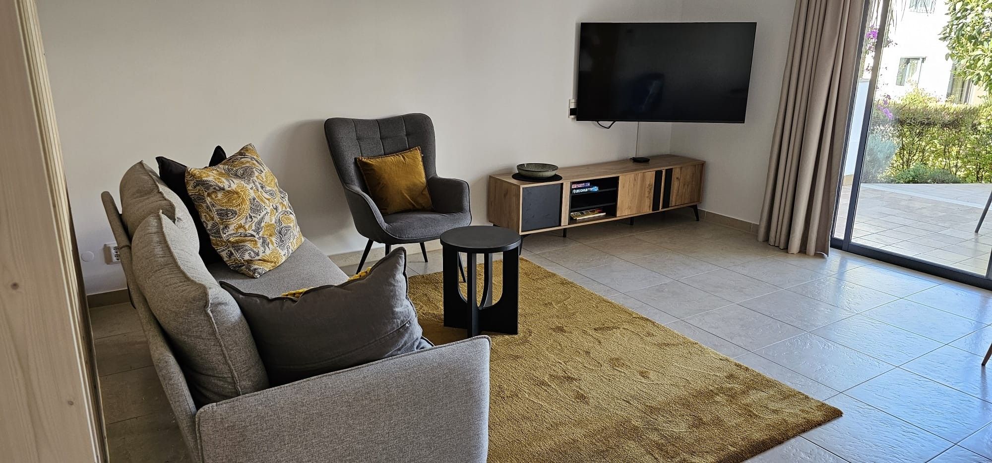 A living room with a sofa, armchair, and a TV on a stand.