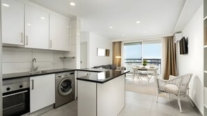 A modern kitchen with a built-in washing machine, a dining area with a view, and a balcony with a chair. - Apartment 'Vista Bonita' with Sea View, Wi-Fi and Air Conditioning (Portimão)