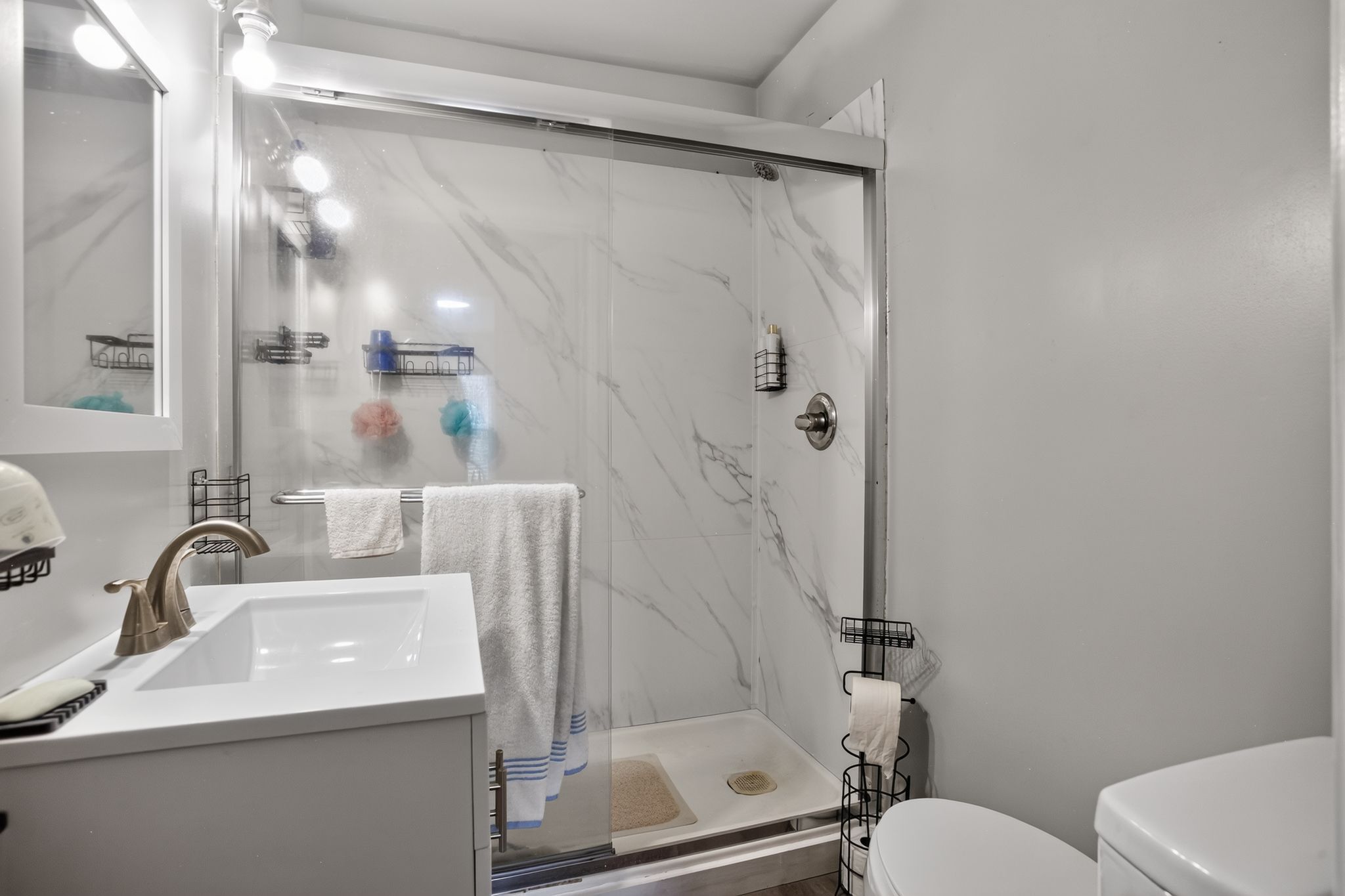 A bathroom with a glass-enclosed shower, a sink with a faucet, and a toilet.