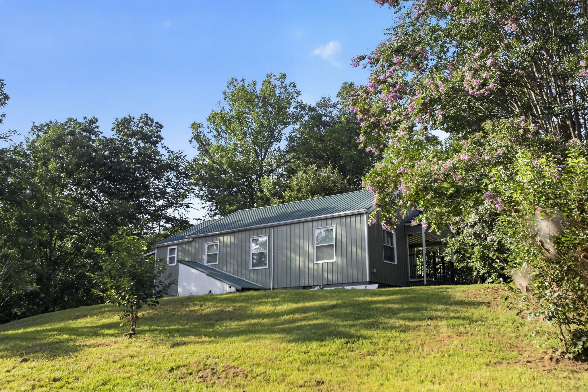 A single-story building with a sloped roof, surrounded by trees and grass.