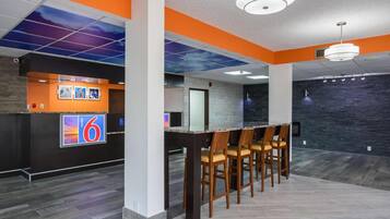 A modern interior with a reception desk, bar area, and seating.