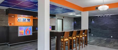 A modern interior with a reception desk, bar area, and seating.