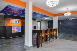 Un interior moderno con mostrador de recepción, zona de bar y asientos.