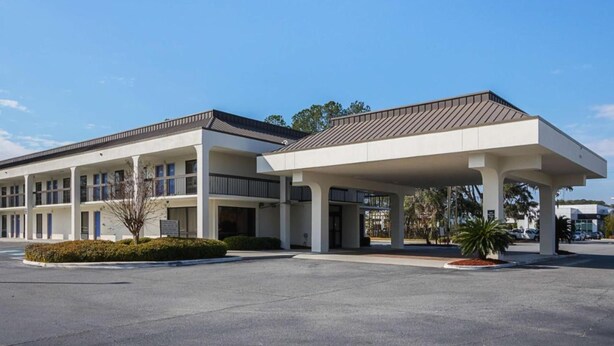 A two-story hotel with a covered parking area and a landscaped entrance. - Cozy King Bed|Free Parking & Wifi (Savannah GA)