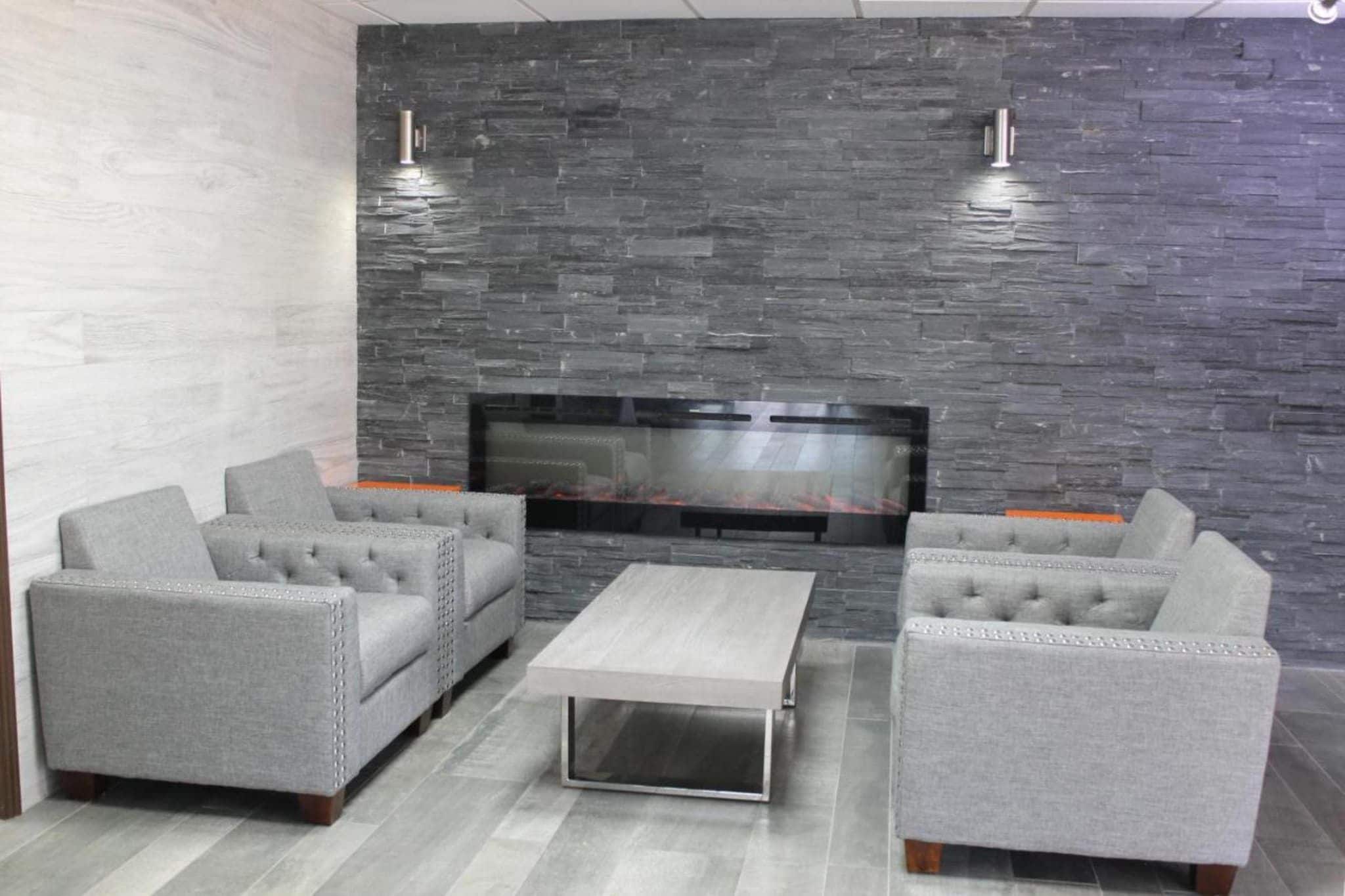 A modern living room with grey upholstered sofas, a flat-screen TV, and a stone wall.