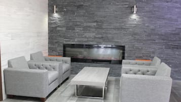A modern living room with grey upholstered sofas, a flat-screen TV, and a stone wall.