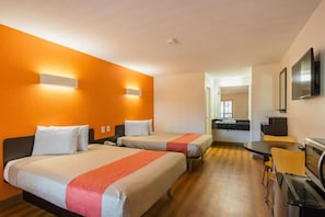 Habitación de hotel con dos camas, una kitchenette pequeña y un comedor.
