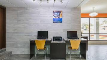 Zona de recepción con dos mostradores, cada uno con una computadora y una silla. Hay un cartel en la pared sobre los mostradores.