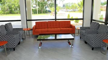 A modern interior with a sofa set and chairs, a coffee table, and large windows offering a view of the outdoors.