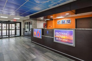 A hotel reception area with a digital sign displaying the number 6, a wheelchair accessibility sign, and a motivational poster. - 2 Queen Beds | Premium, Micfridge (Savannah GA)