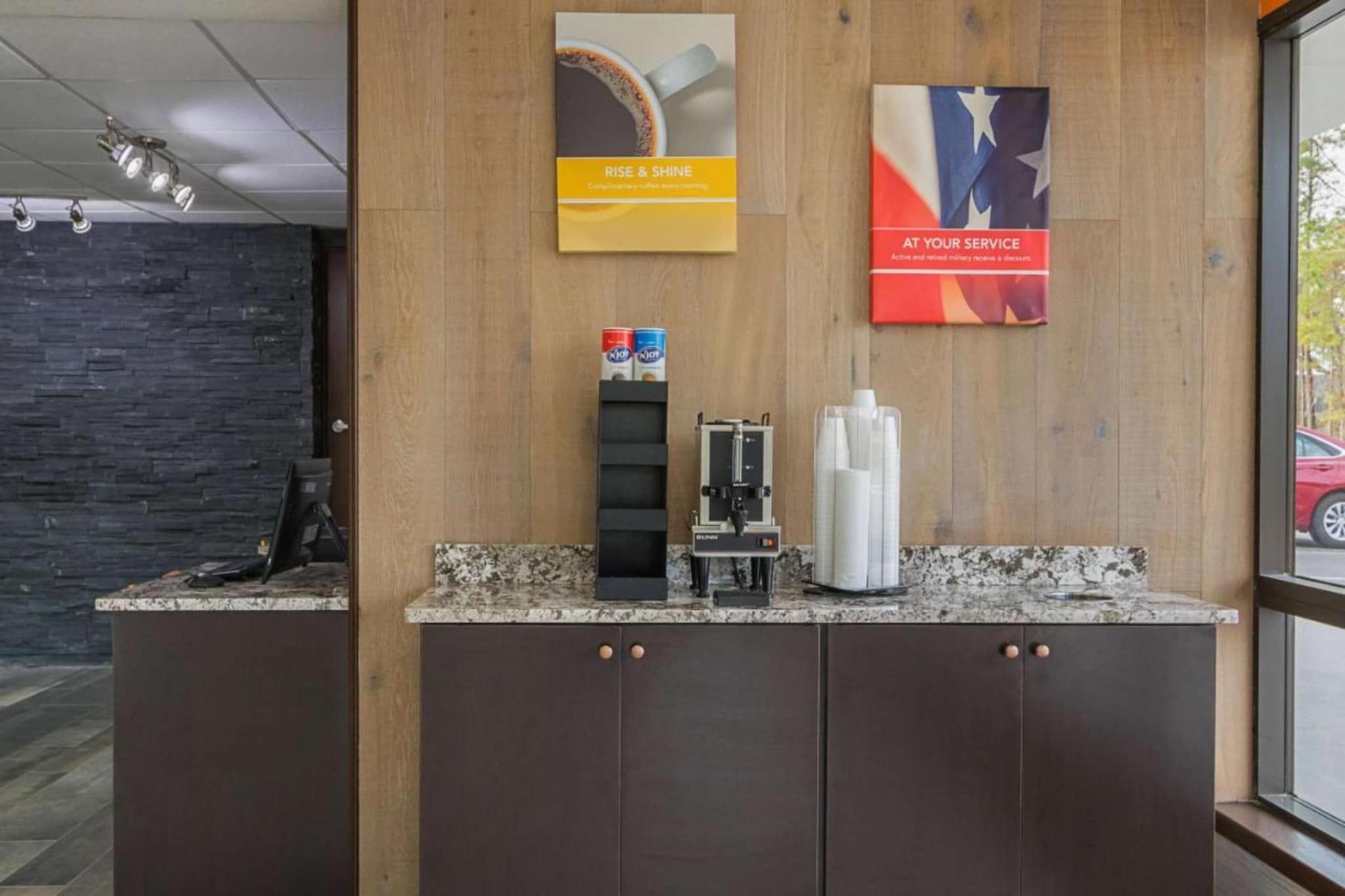 A reception area with a coffee machine, a bottle of hand sanitizer, and a coffee cup on the counter.