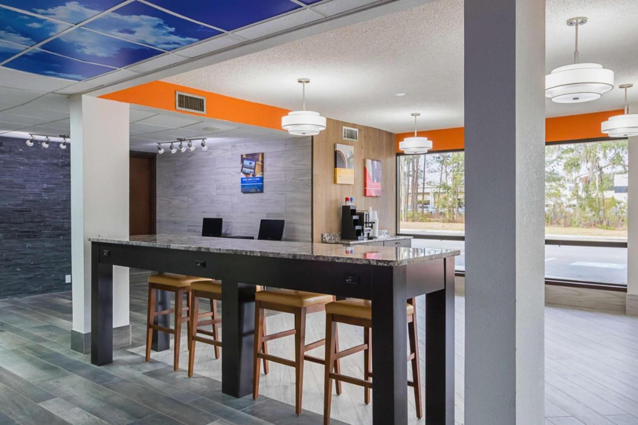 A modern bar area with a marble countertop, wooden stools, and pendant lighting.