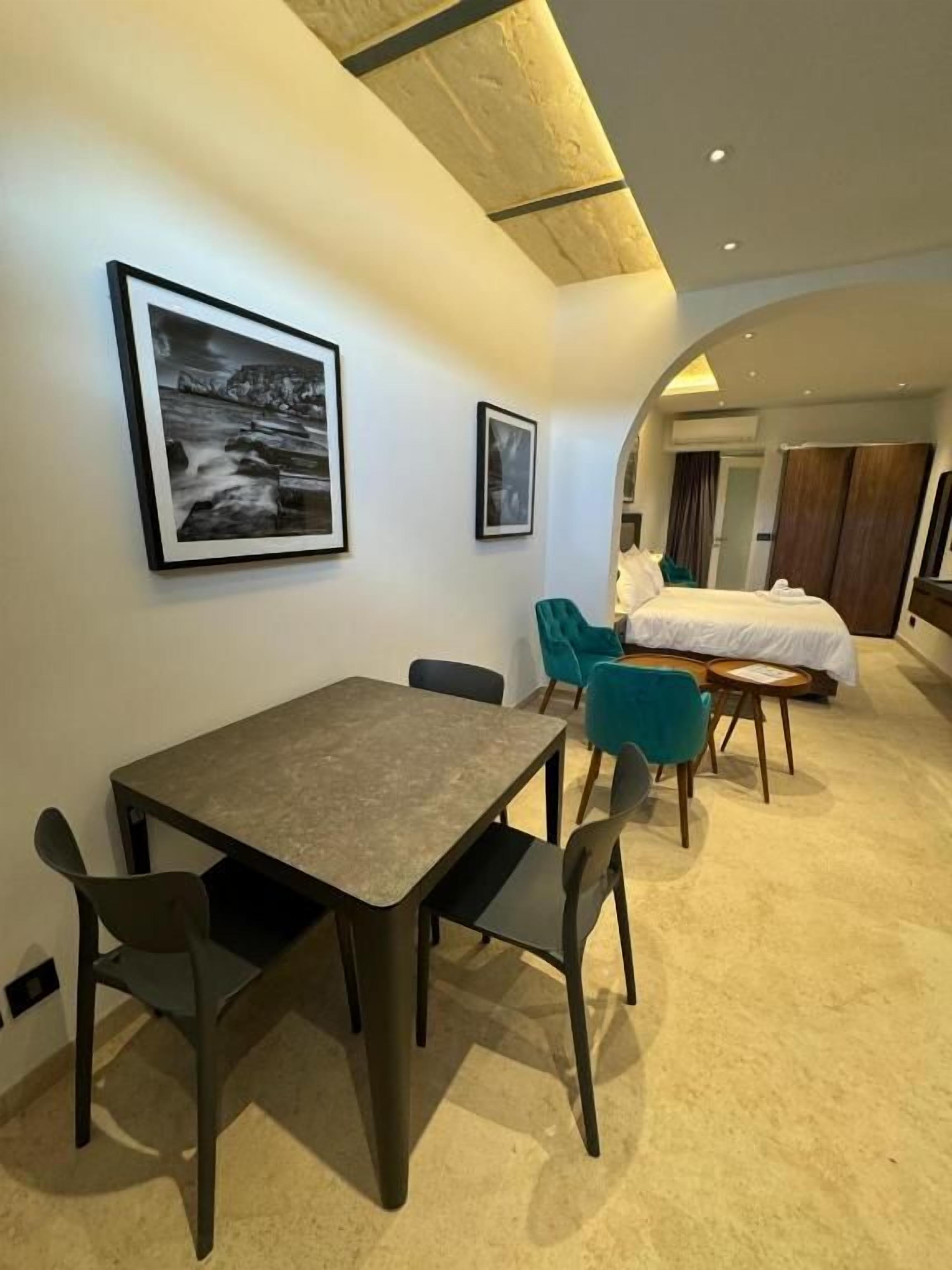 Ein modernes Hotelzimmer mit Essbereich, einem Bett und einem großen Fenster.