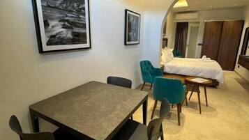 Ein modernes Hotelzimmer mit Essbereich, einem Bett und einem großen Fenster.