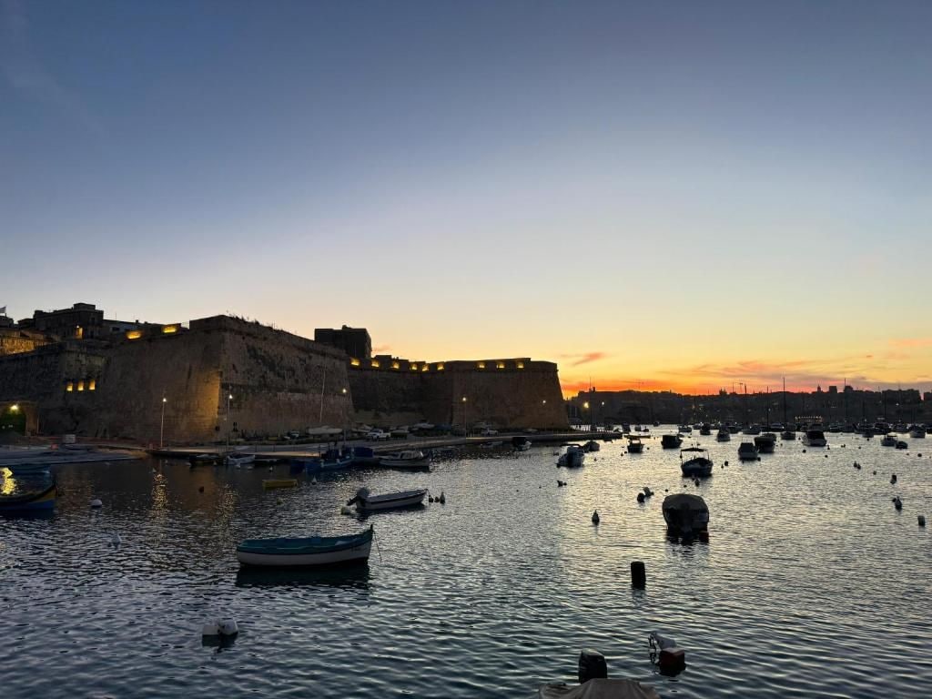 Un porto con barche e un edificio fortificato al tramonto.