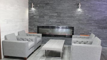 A modern living room with a stone wall, grey upholstered sofas, a flat-screen TV, and a coffee table.