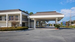 A hotel with a covered parking area, multiple floors, and a clear sky. - 1 King Bed | Premium, Micfridge (Savannah GA)