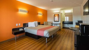 A hotel room with a bed, bedside table, desk, and a TV. - 1 King Bed | Mobility Accessible Tub, Nsmk (Savannah GA)