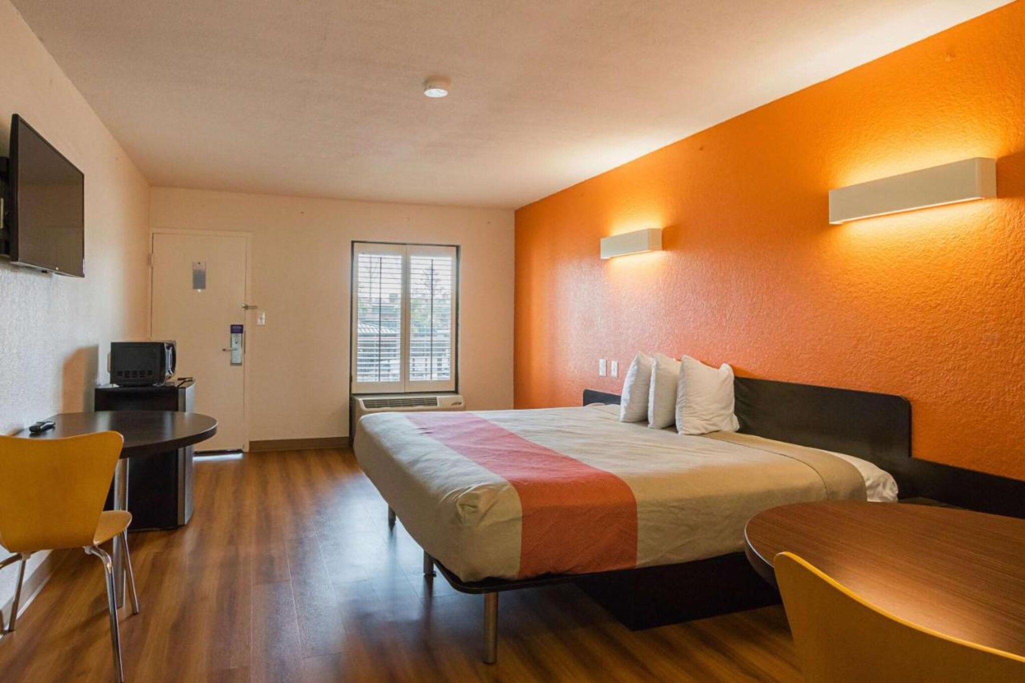 Una habitación de hotel con una cama, un escritorio, una silla y un televisor.
