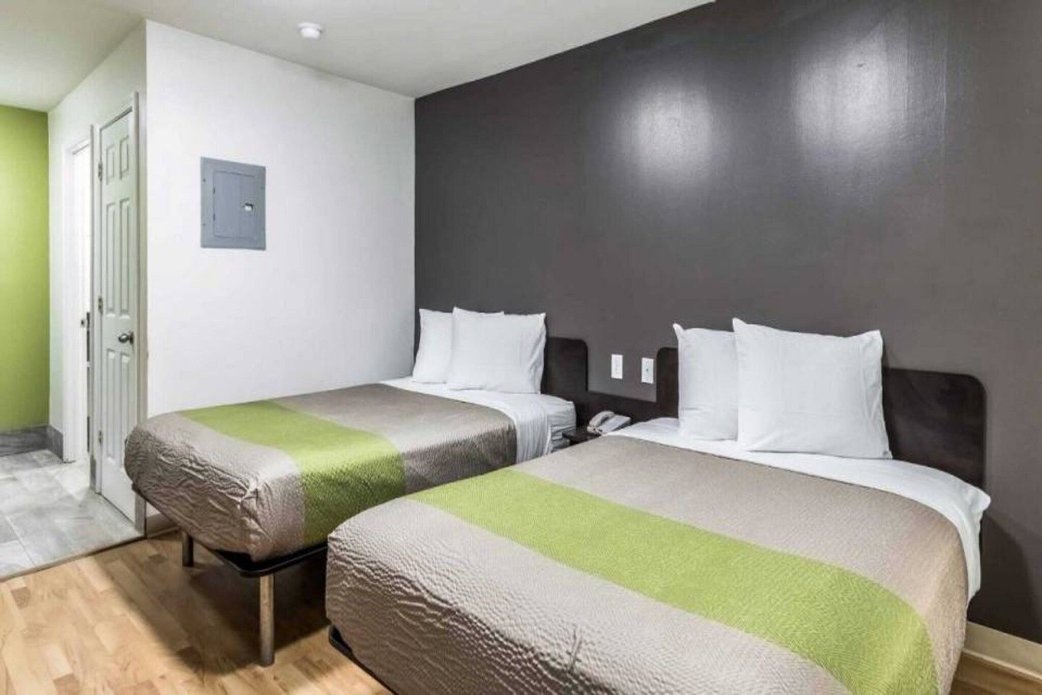 Una habitación de hotel con dos camas, una puerta y un interruptor de luz en la pared.