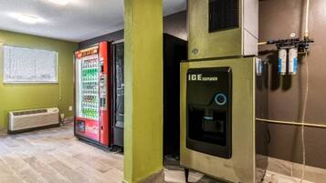 A room with a vending machine, a water dispenser, and a wall-mounted air conditioning unit.