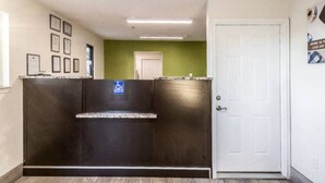 A reception area with a reception desk, a wheelchair accessibility sign, framed certificates on the wall, a green accent wall, and a white door. - 2 full beds|kitchen|Non-smoking (Savannah GA)