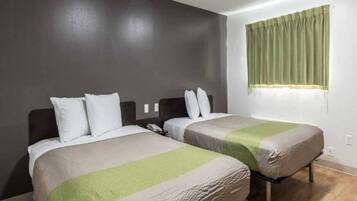 Una habitación de hotel con dos camas, una cortina verde y un teléfono en la mesita de noche.