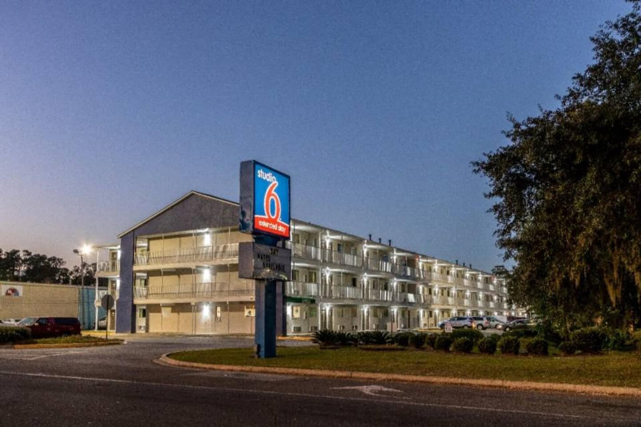 Un hôtel à plusieurs étages, avec une enseigne bien visible indiquant « Studio 6 » et un parking situé devant.