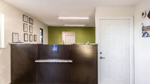 A reception area with a dark reception desk, a white door, and framed certificates on the wall. - 1 queen bed|mobili access|kitchen|Nsmk (Savannah GA)