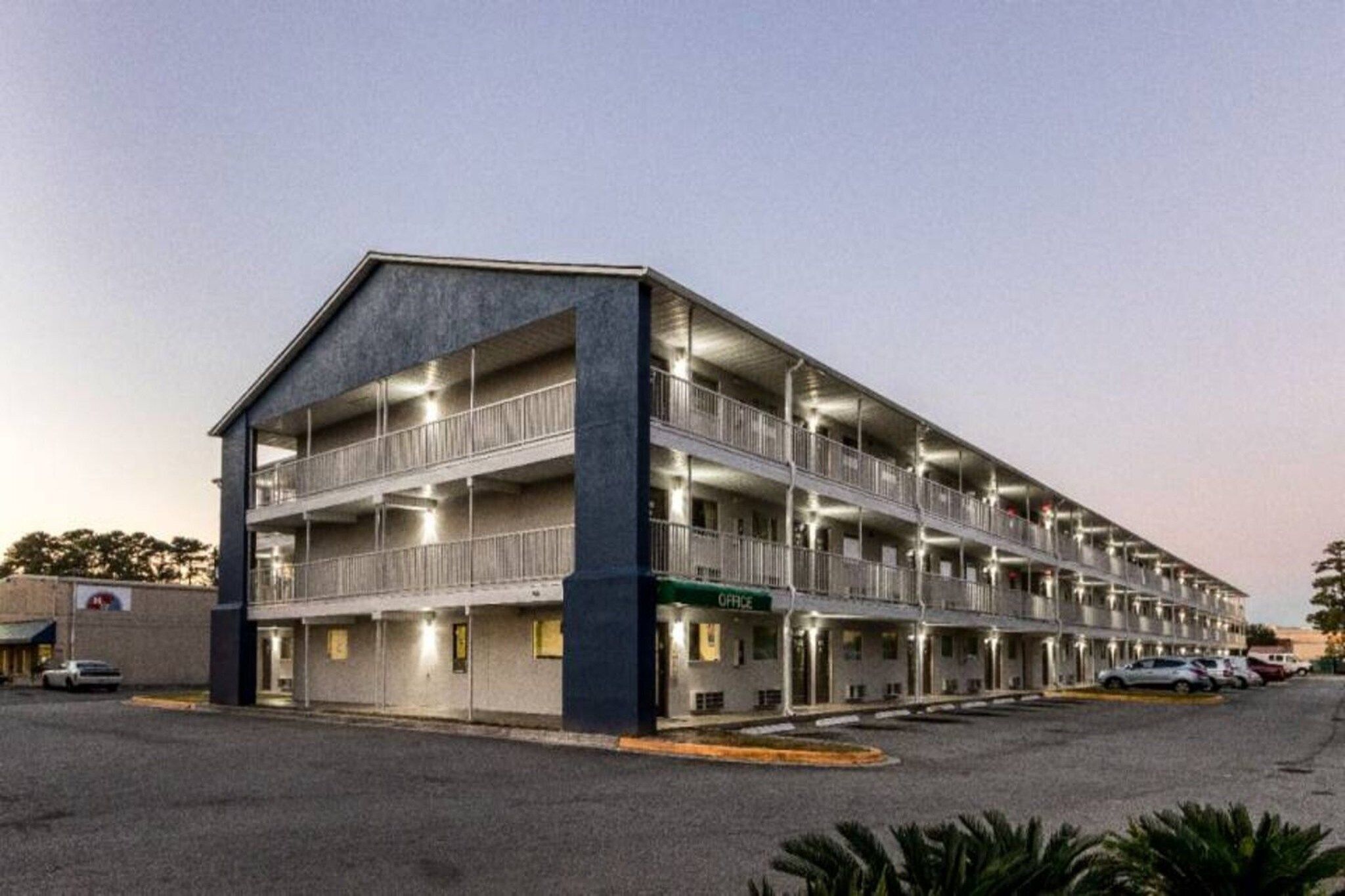 A multi-story motel with balconies, a parking lot, and a visible office entrance.