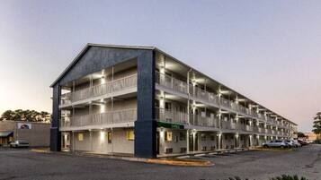 A multi-story motel with a central office, multiple balconies, and a parking lot.