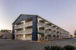Un motel de varios pisos con una oficina central, múltiples balcones y un estacionamiento.