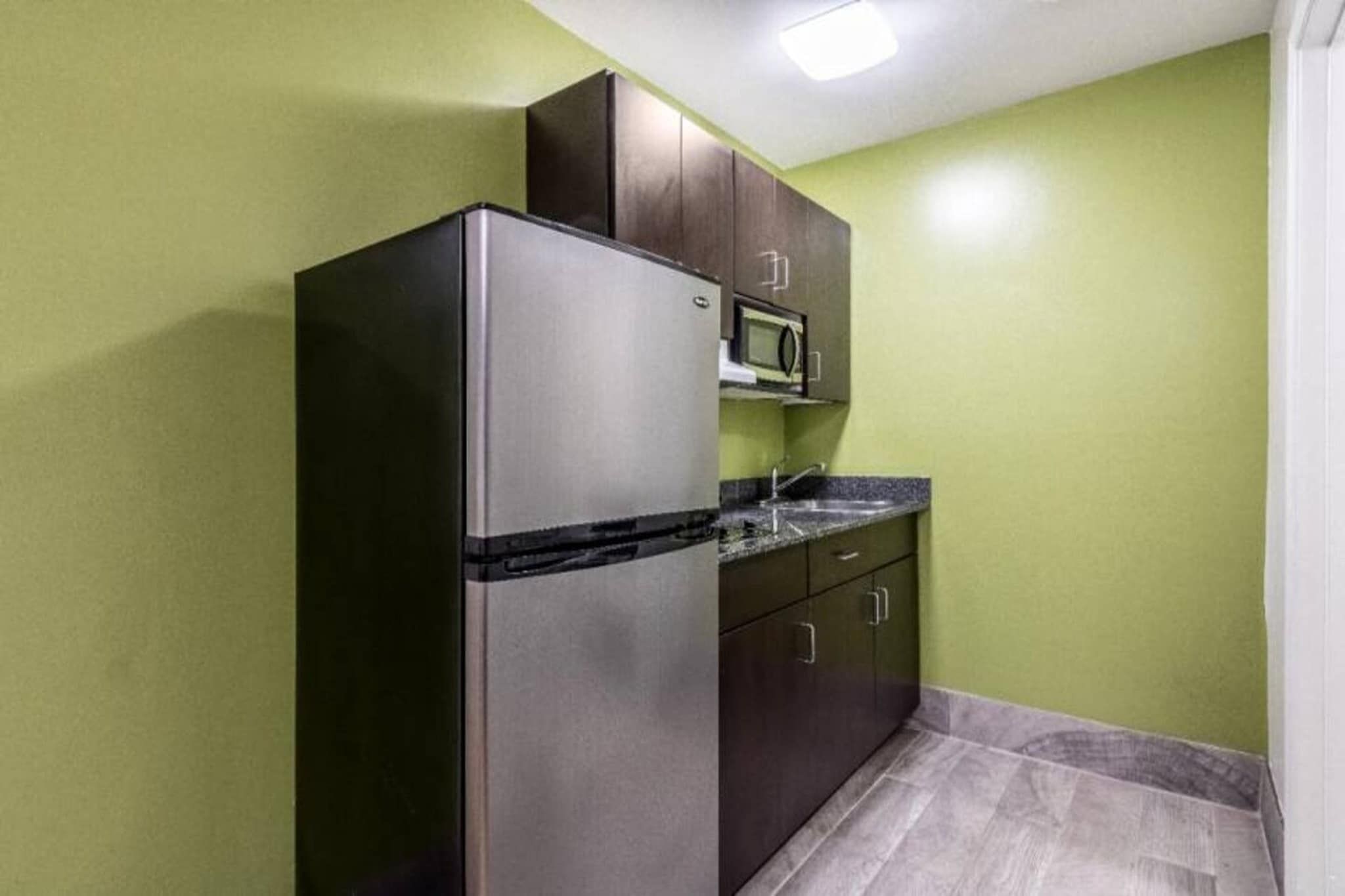A compact kitchen with a refrigerator, microwave, and cabinets.