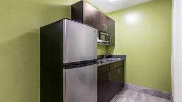 A compact kitchen with a refrigerator, microwave, and cabinets.
