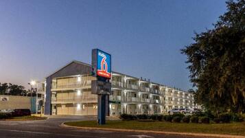 A multi-story hotel with a prominent sign for 'Studio 6' and a parking lot in front.