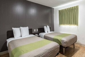 Una habitación de hotel con dos camas, una cortina verde y un teléfono en la mesita de noche.