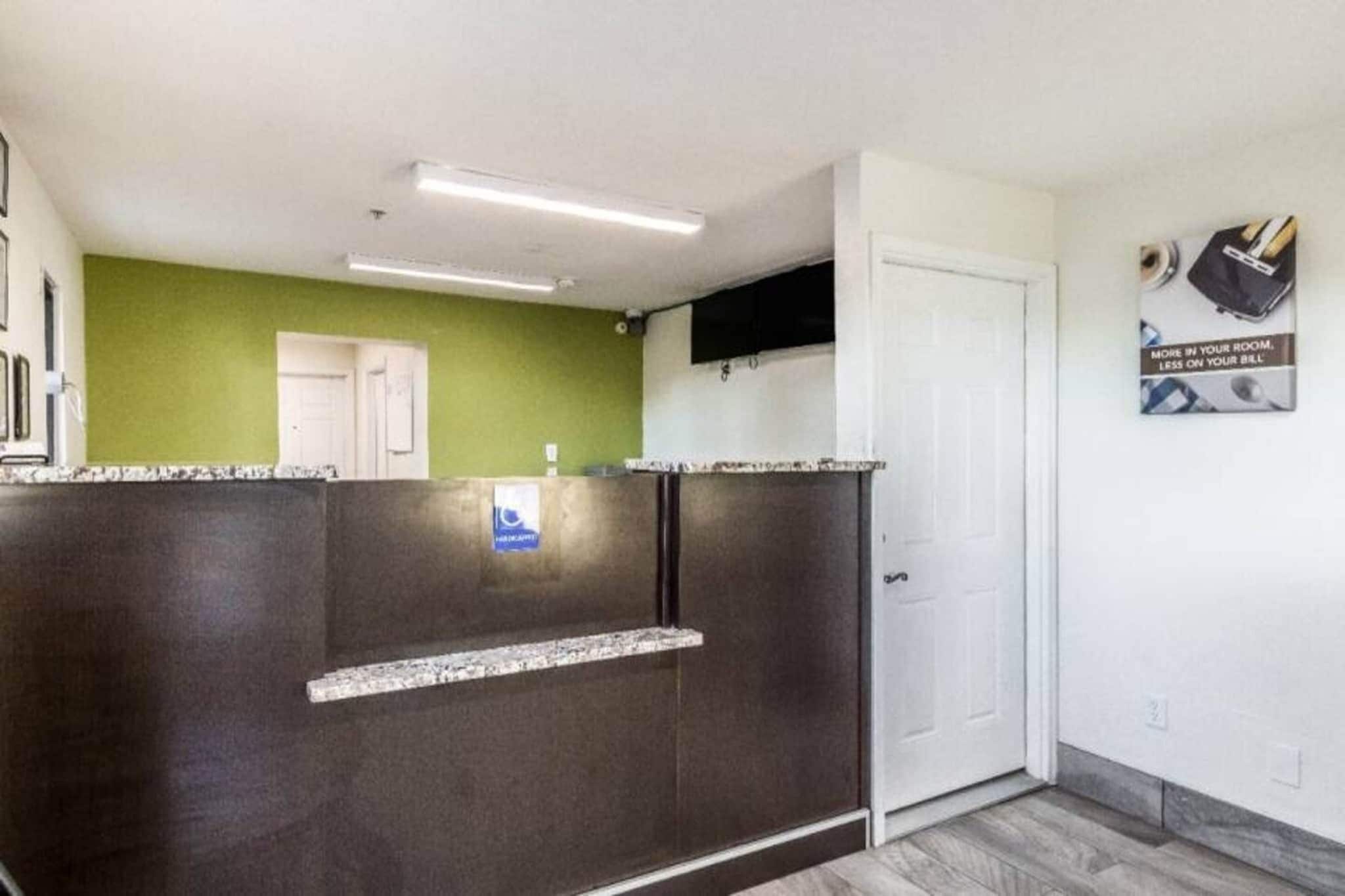 A reception area with a dark counter, a green wall, a white door, and a sign on the wall.
