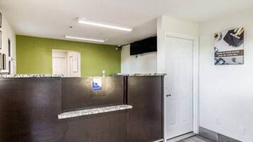 A reception area with a dark counter, a green wall, a white door, and a sign on the wall.