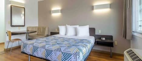 Una habitación de hotel con cama, escritorio, silla y calefactor.