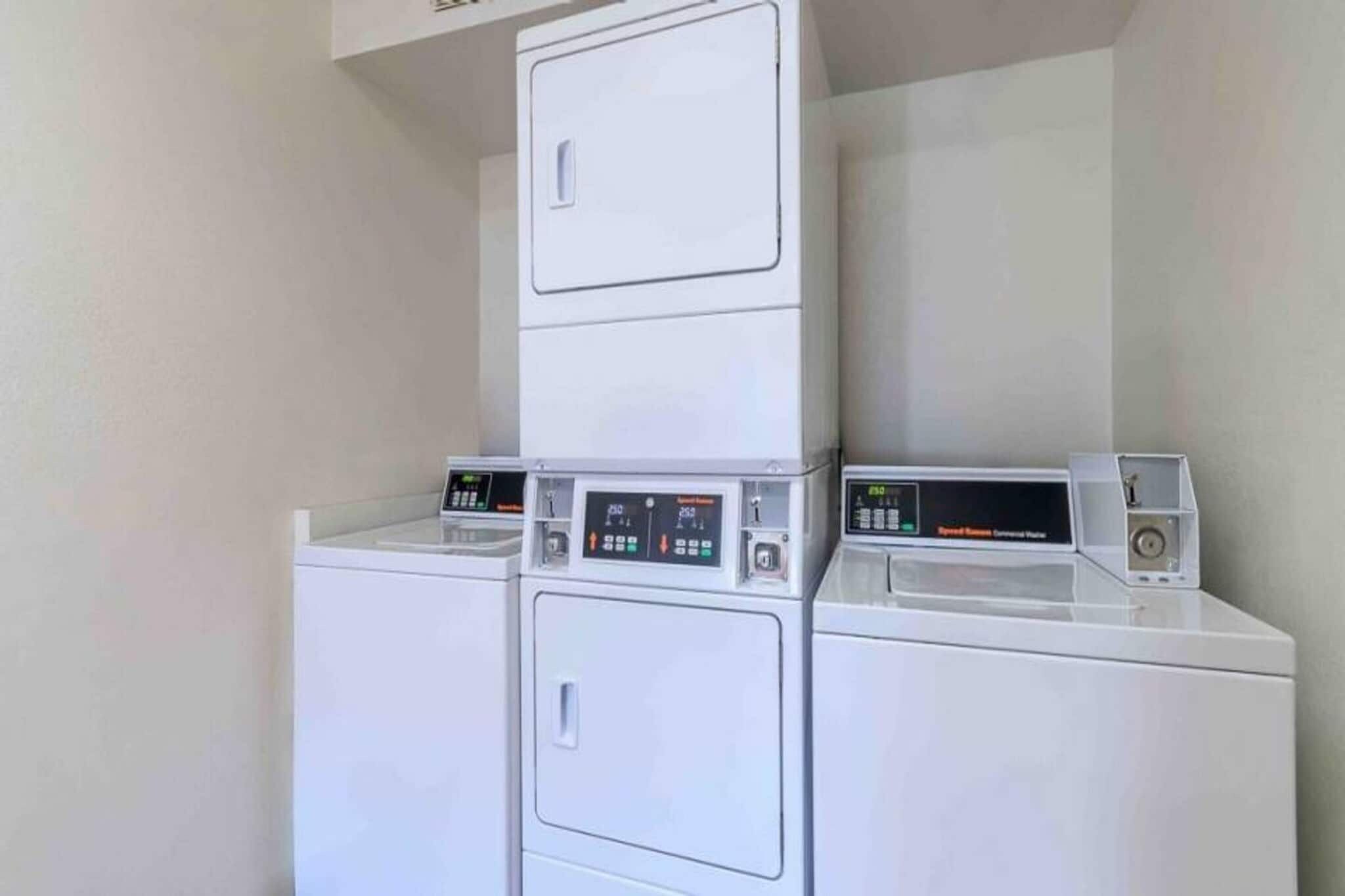 A laundry area with three stacked washers and dryers.
