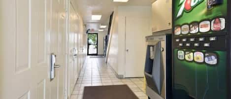 A hallway with a 7UP vending machine, a microwave, and a door at the end.