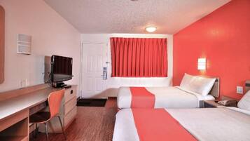 A hotel room with a desk, television, two beds, and a red curtain.