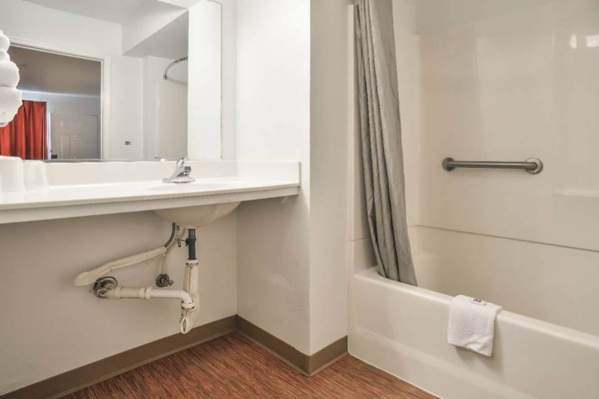 Un baño con lavamanos blanco, espejo y bañera.