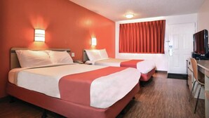 Una camera d'albergo con due letti, una scrivania e un televisore.
