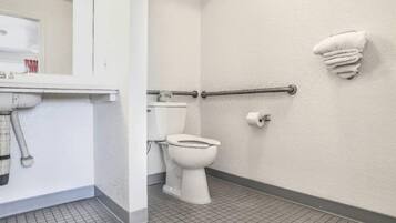 Un baño con inodoro, toallero y barra de apoyo.