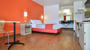 Een hotelkamer met een bed, een bureau, een stoel en een kitchenette.