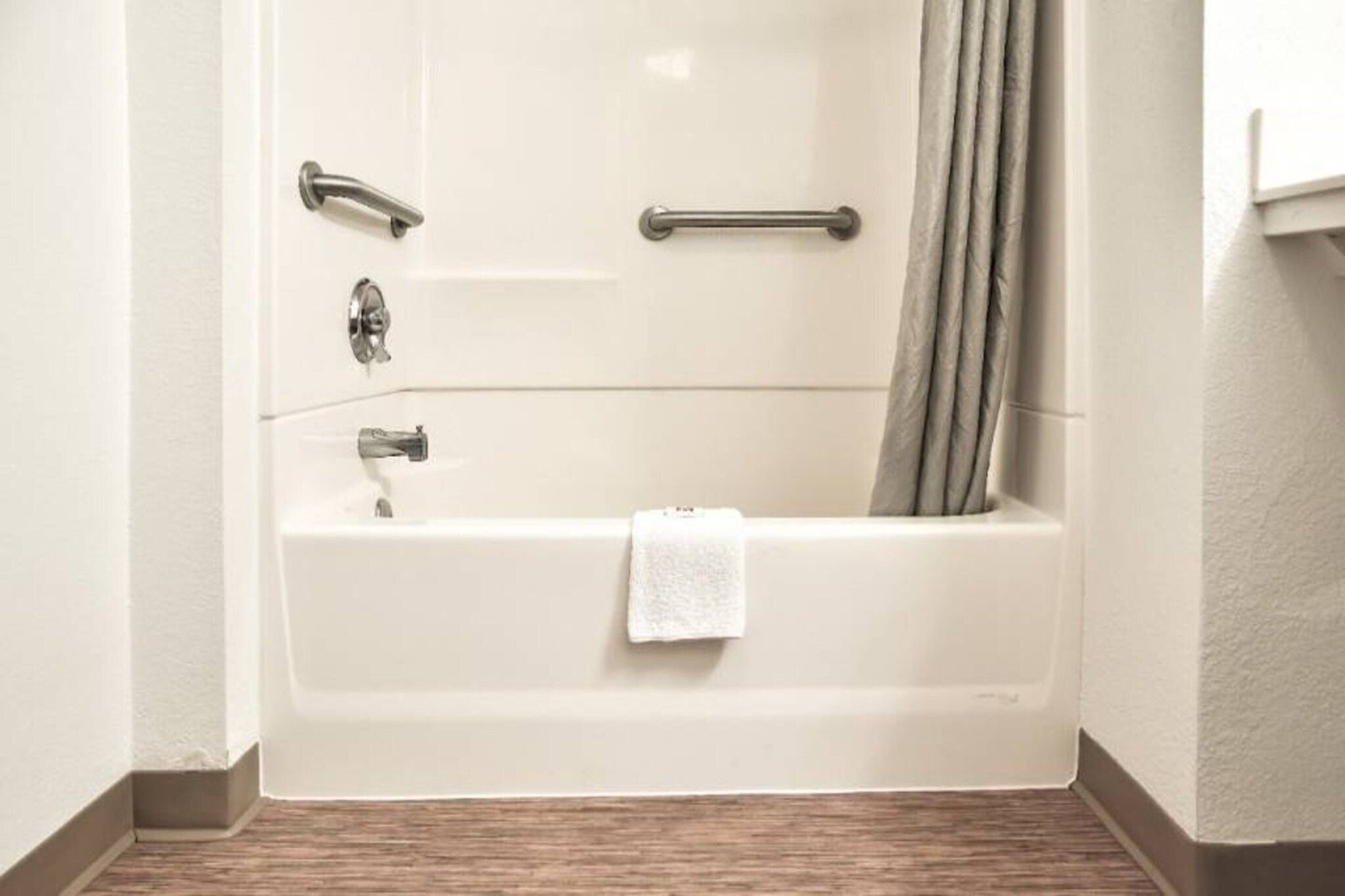 Une salle de bain d’hôtel standard, équipée d’une baignoire, d’un rideau de douche et d’un porte-serviettes.